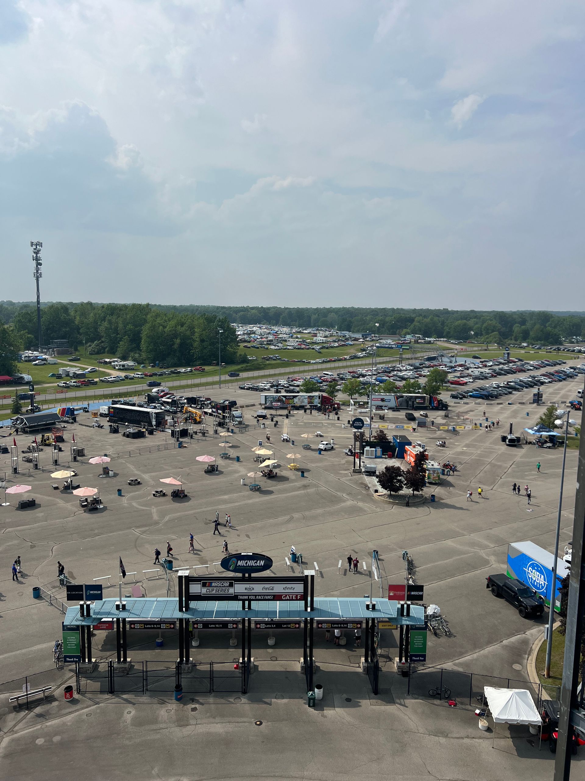 Overhead view of a crowded race track parking lot with a toll booth entrance.