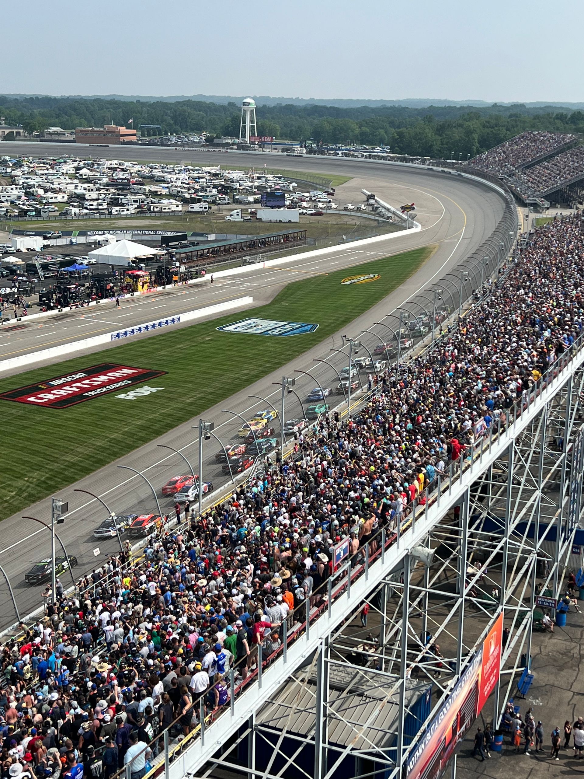 Race cars on track with large crowd at a racetrack.