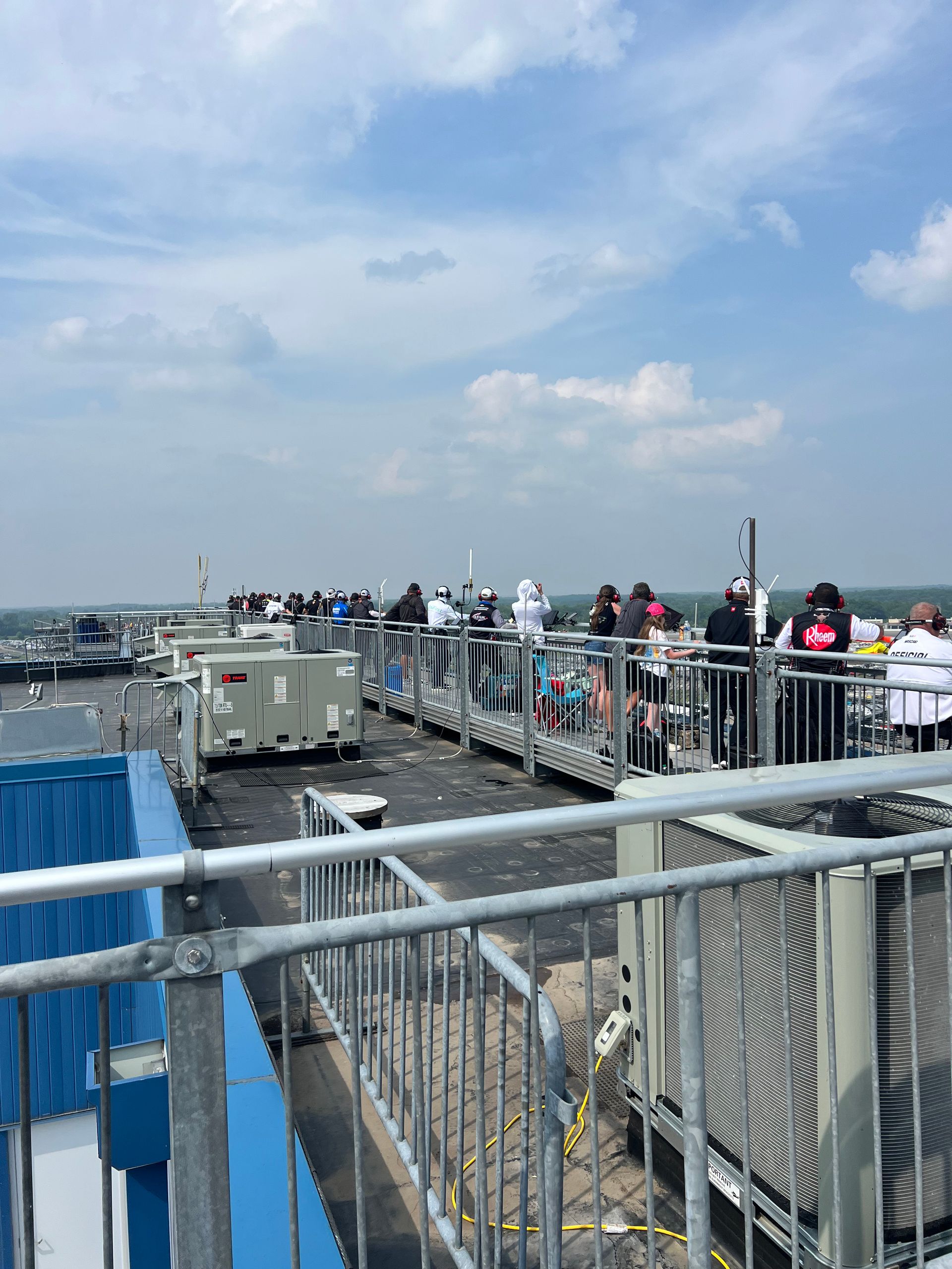 People on a metal walkway, overlooking a dock. Blue sky with clouds.