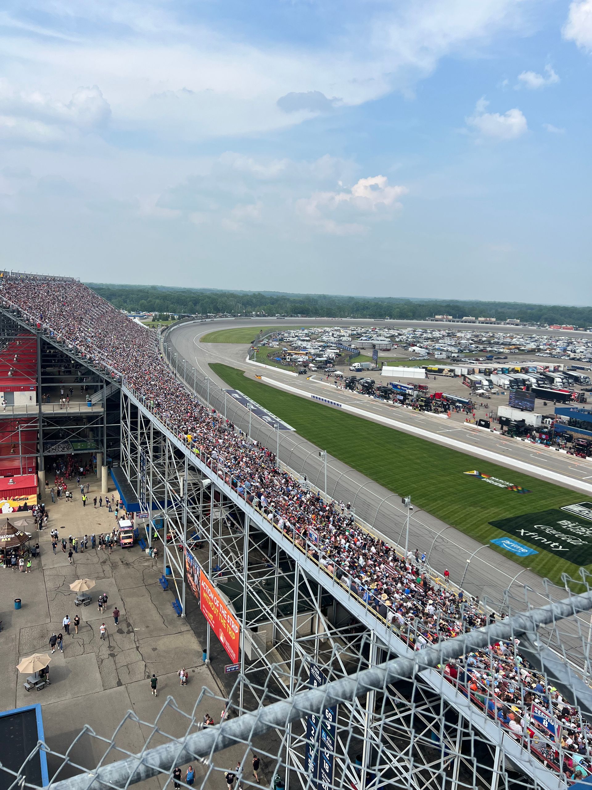 Race track with packed grandstands, large crowd watching, sky overhead.