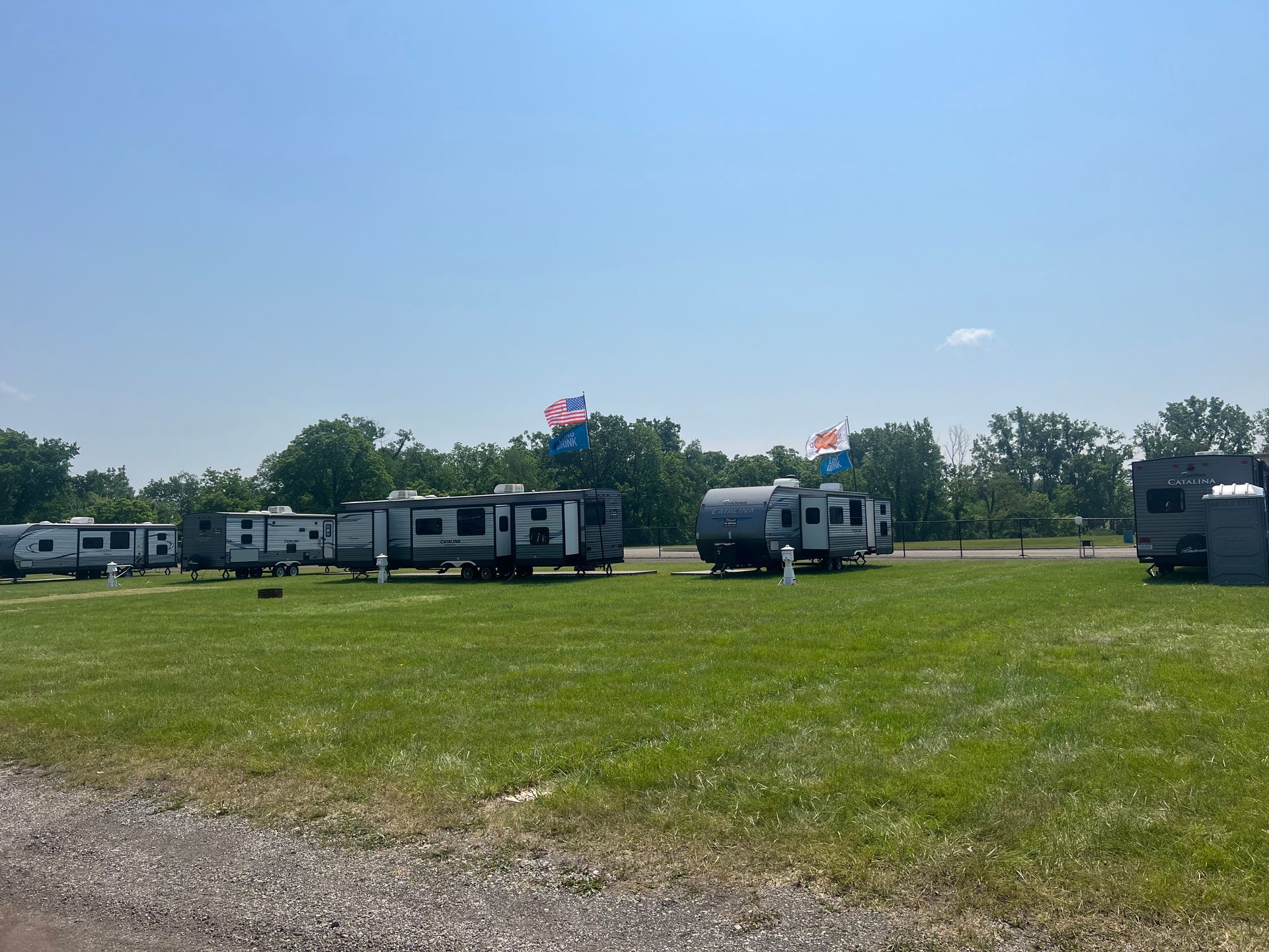 Campground with several RVs parked on green grass under a clear blue sky.