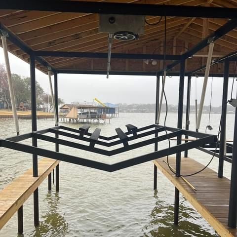 A boat lift is sitting on top of a wooden dock next to a body of water.