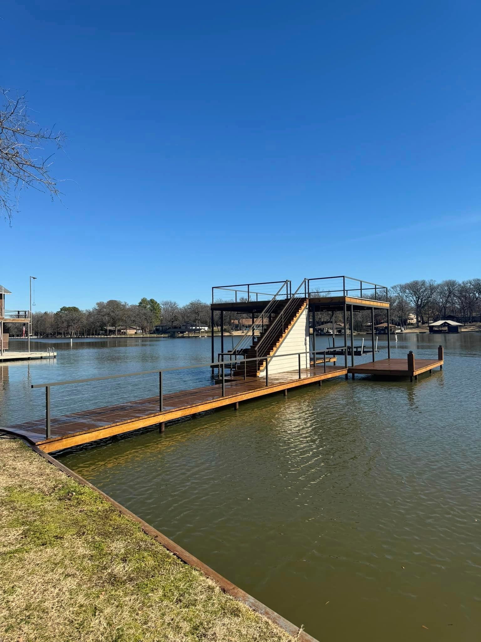 A dock with stairs leading up to a house on a lake.