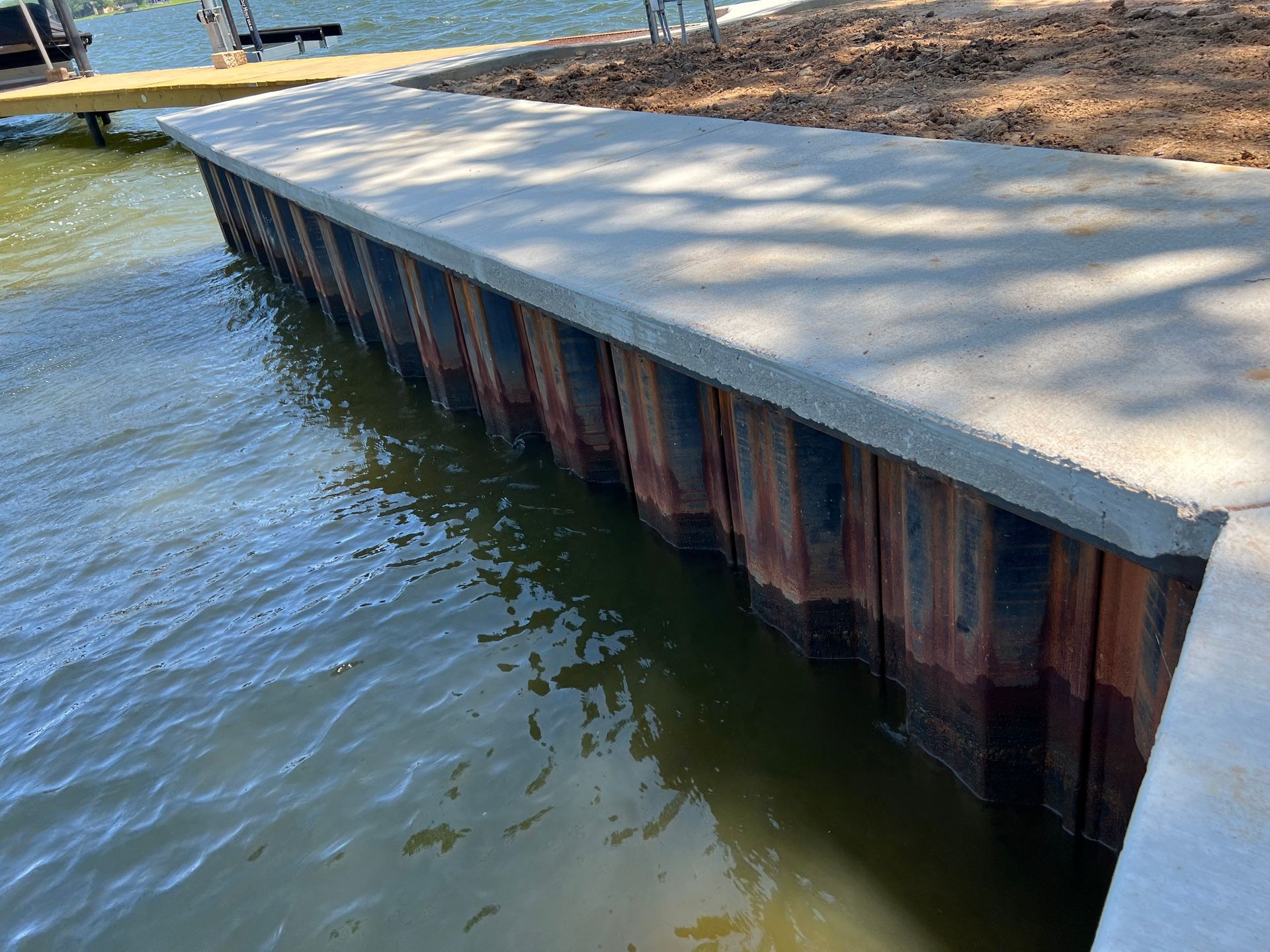 A wooden dock with a concrete walkway next to a body of water.