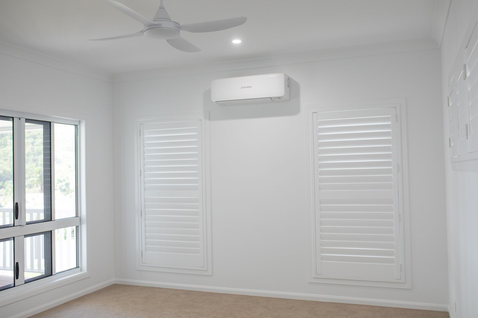White Room With Closed Shuttered Windows, Air Conditioner, and Ceiling Fan — Jones Building Group in Yeppoon, QLD