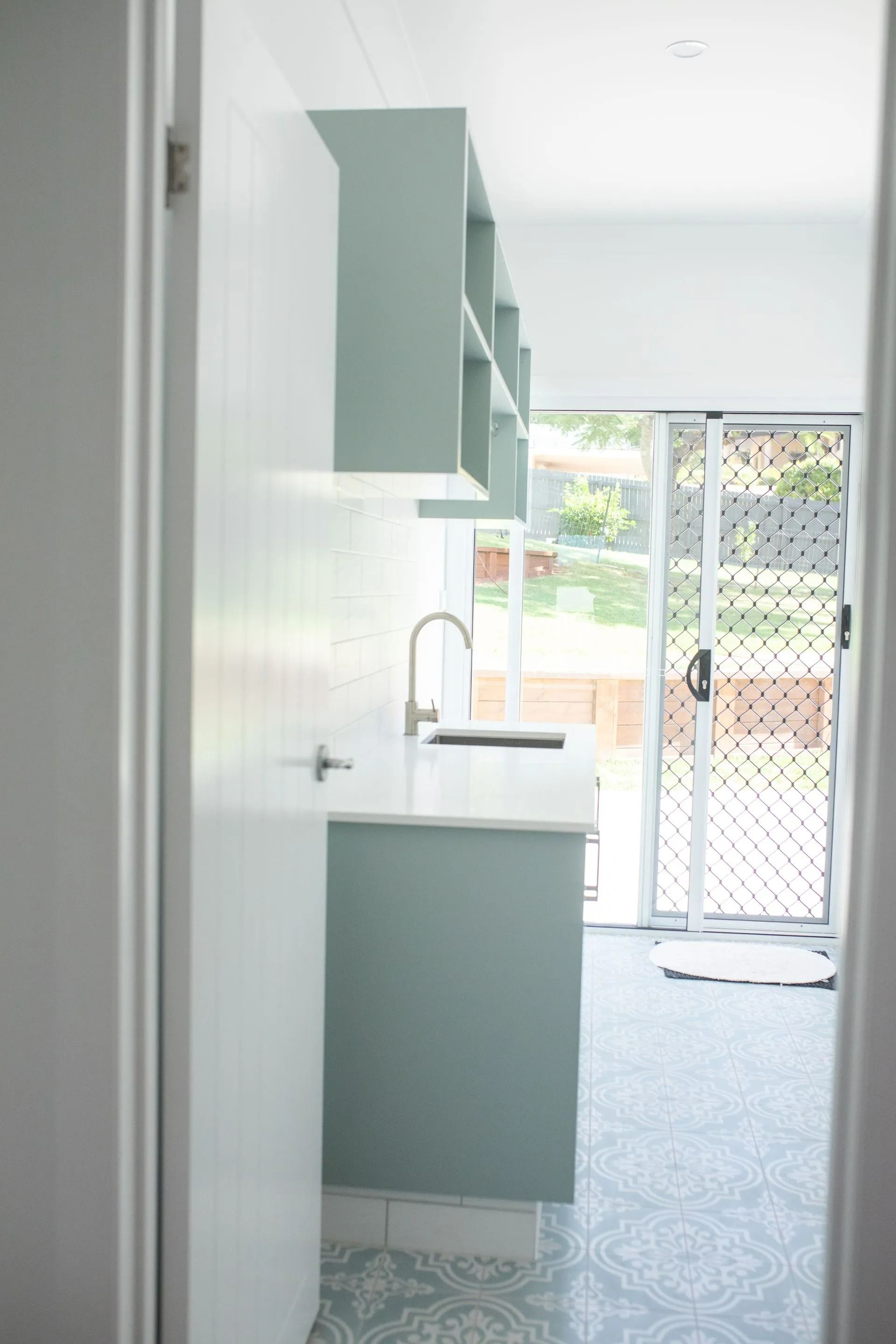 A Small Kitchen Space With Light Blue Cabinets and White Countertop — Jones Building Group in Yeppoon, QLD