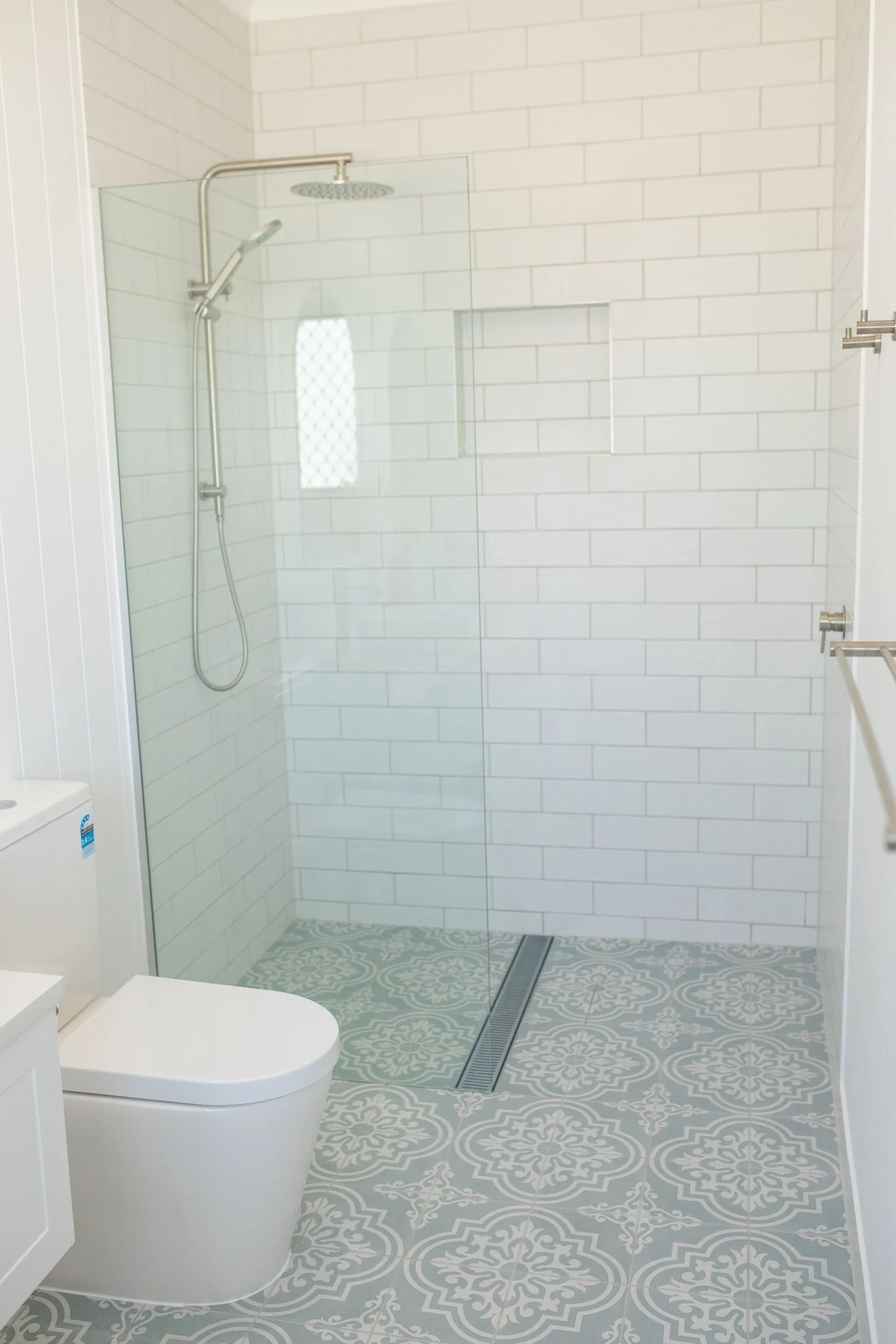 Bathroom With White Subway Tile Walls, Patterned Floor, Glass Shower, and Toilet — Jones Building Group in Yeppoon, QLD