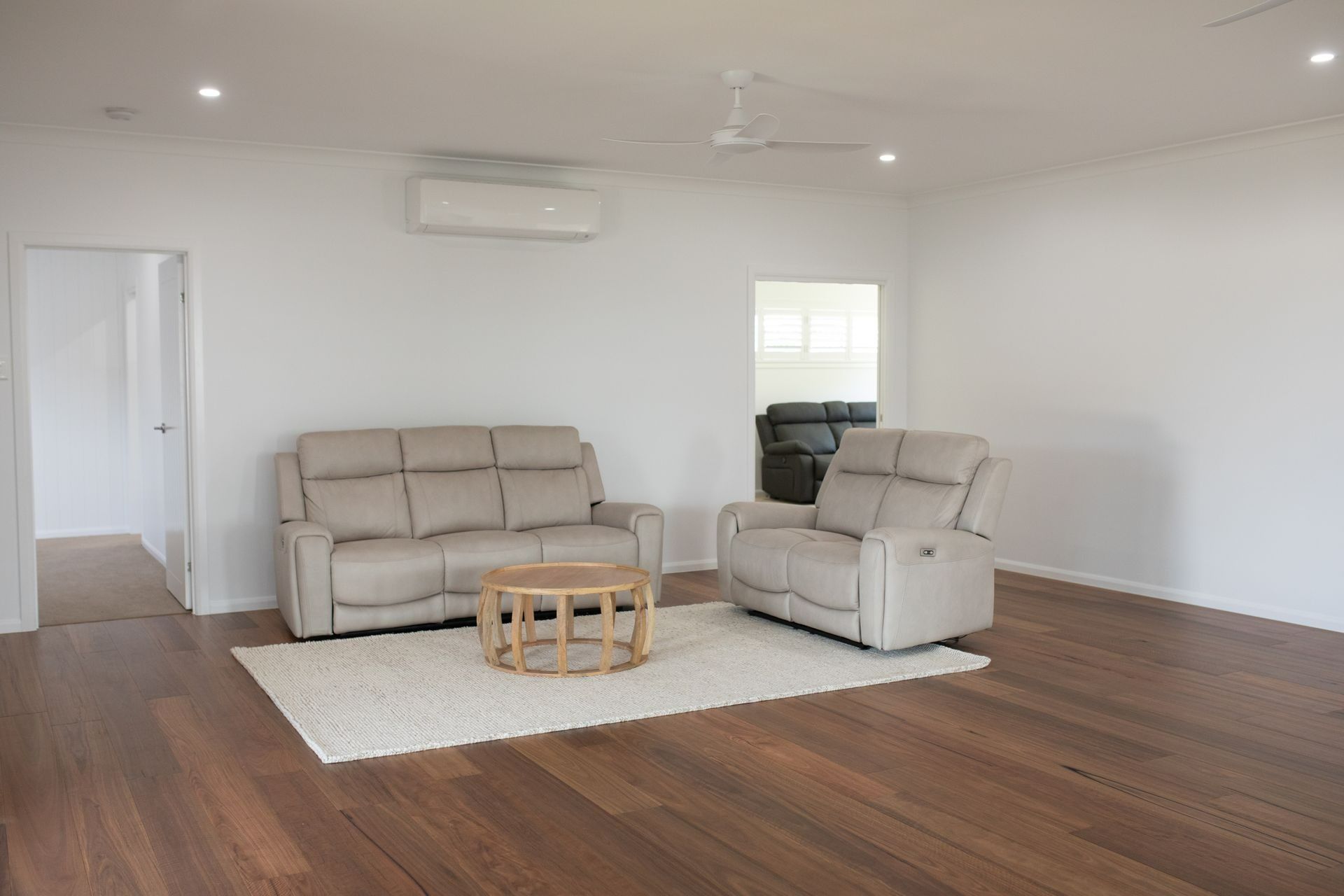 Living Room With a Beige Sofa, Recliner, and Round Coffee Table — Jones Building Group in Yeppoon, QLD