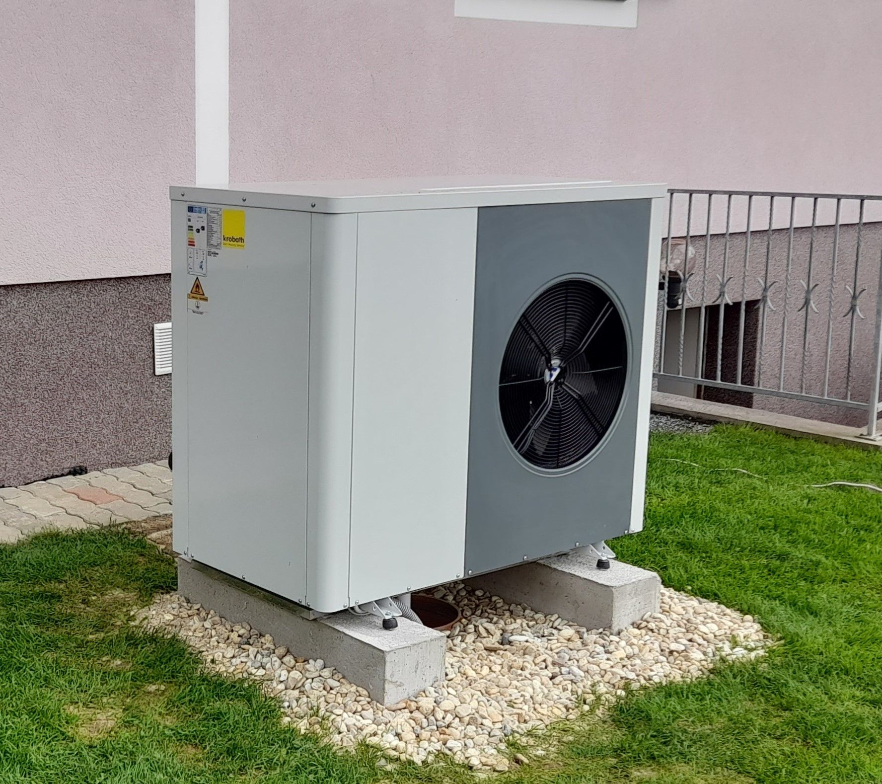 Eine große Klimaanlage steht im Gras vor einem Gebäude