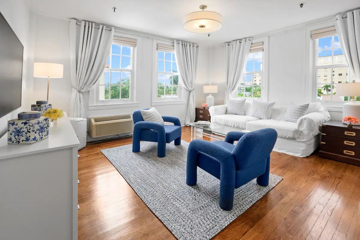 A living room with a couch , two chairs , a rug and a television.