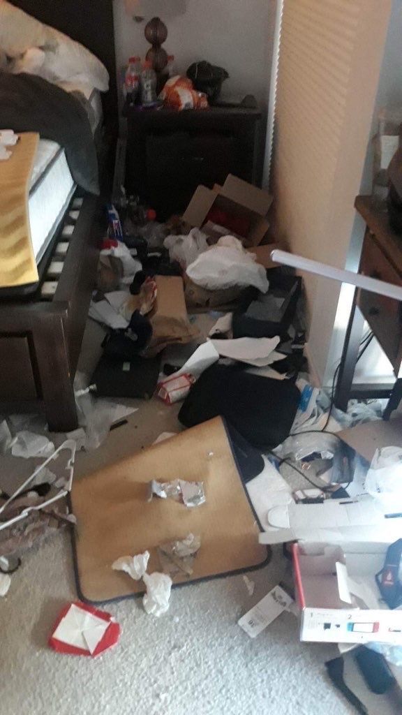 A bedroom with a lot of trash on the floor and a bed.