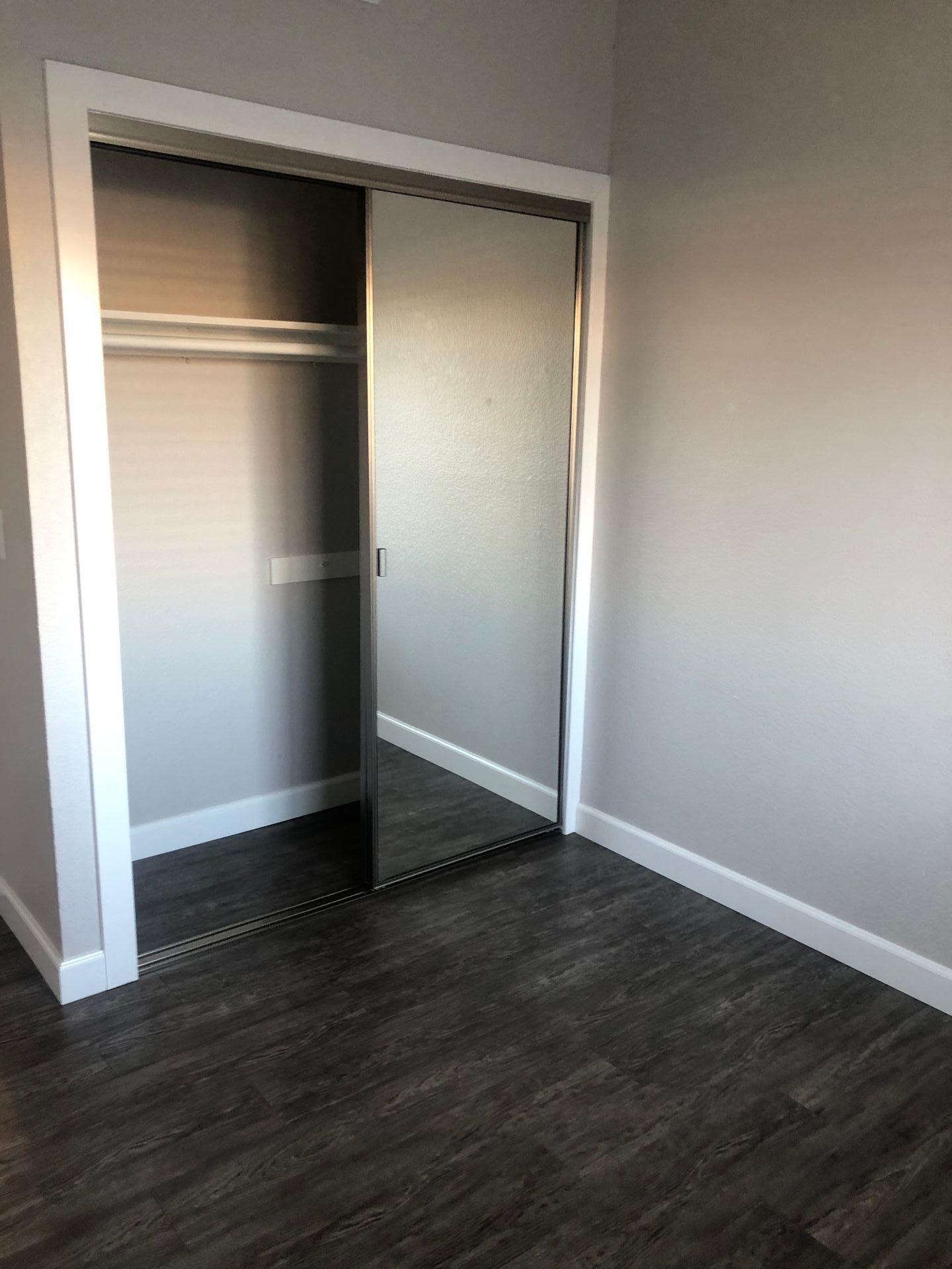 An empty bedroom with a closet and a mirror.