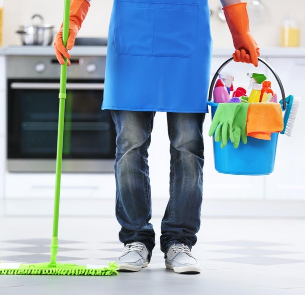 A person holding a mop and a bucket of cleaning supplies