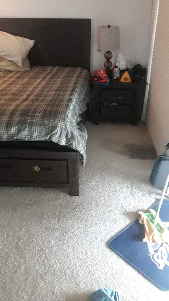 A bedroom with a bed , nightstand and lamp.