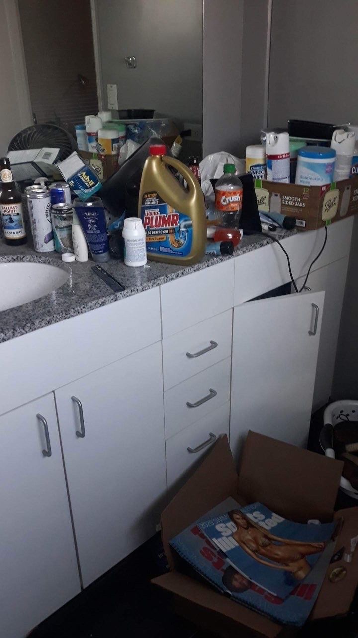 A messy bathroom with a box of bananas on the floor