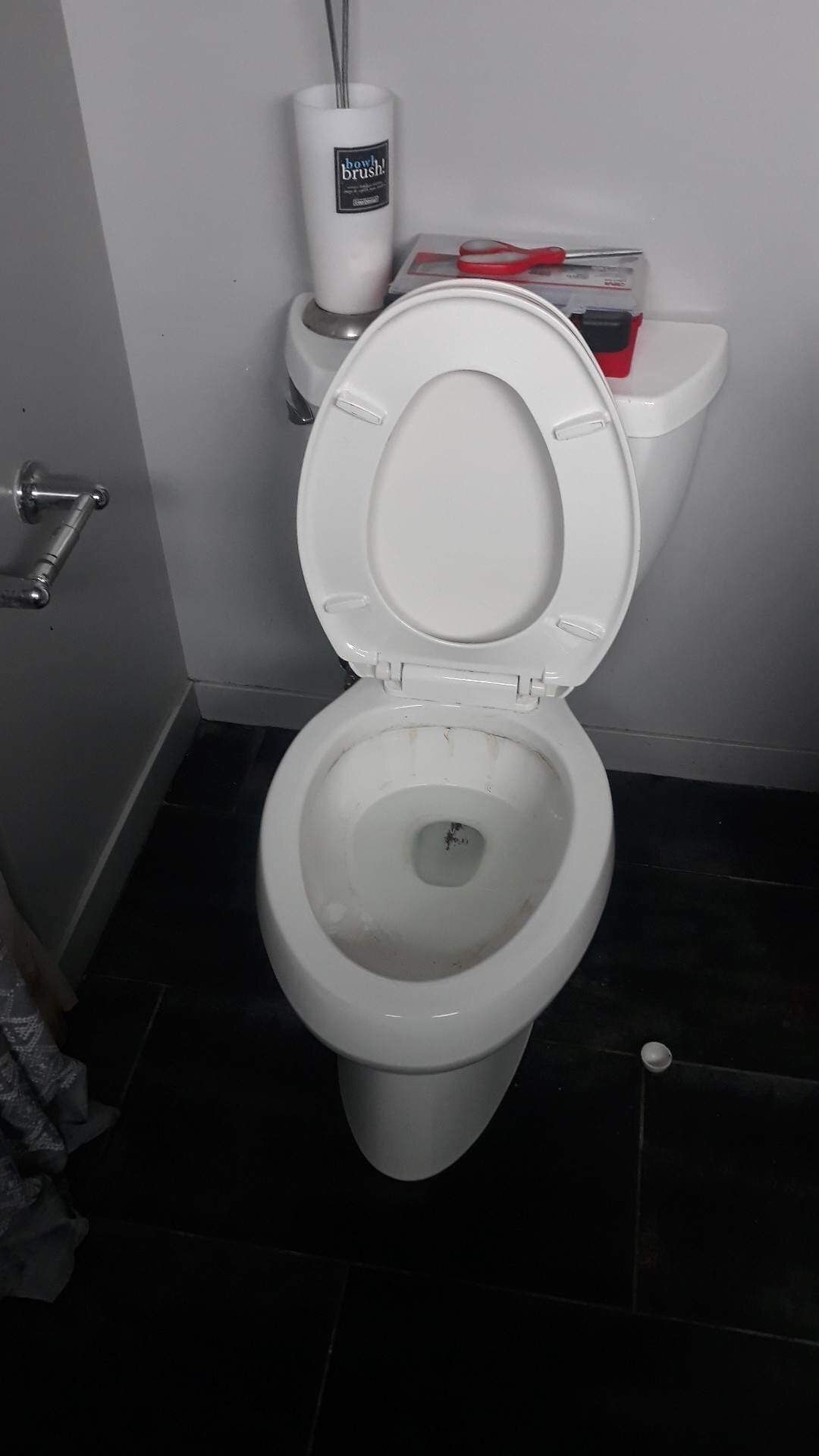 A white toilet with the lid open in a bathroom.