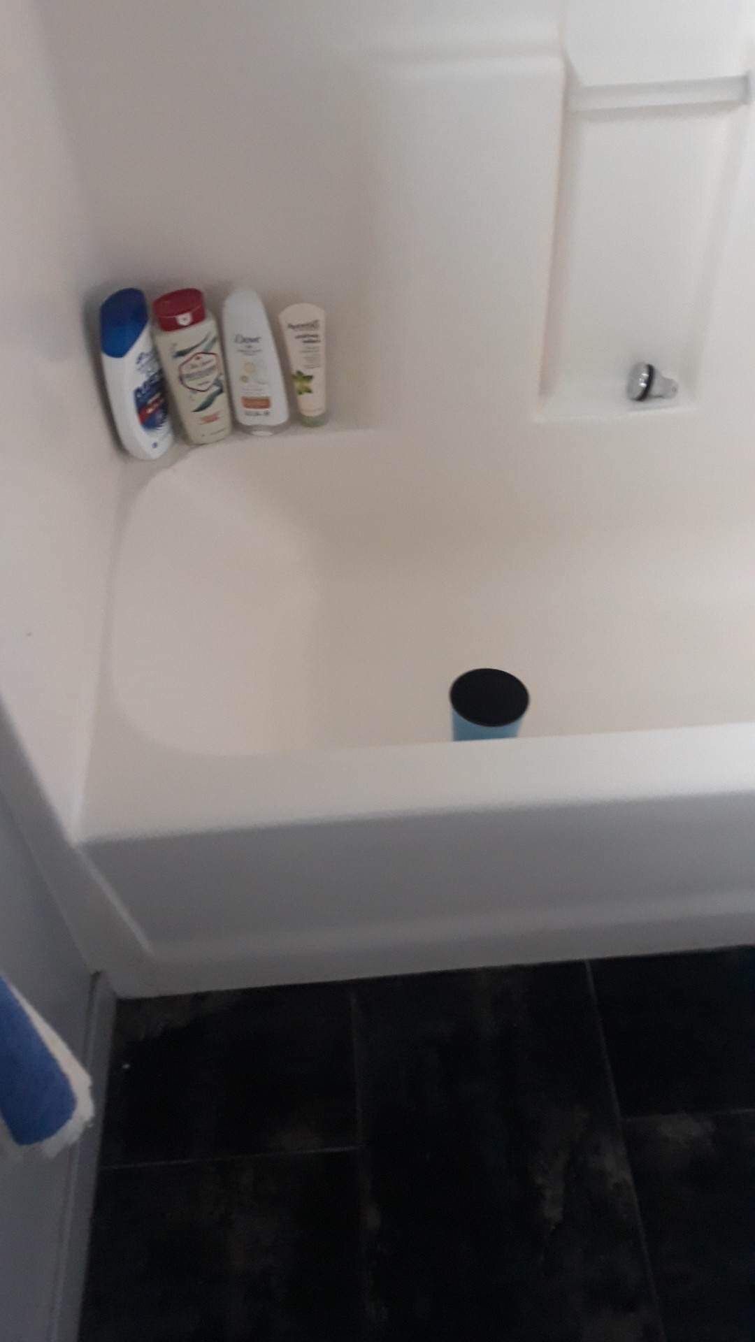 A bathtub with bottles of shampoo and conditioner on the shelf.