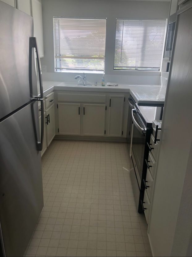 A kitchen with a refrigerator , stove , sink and window.