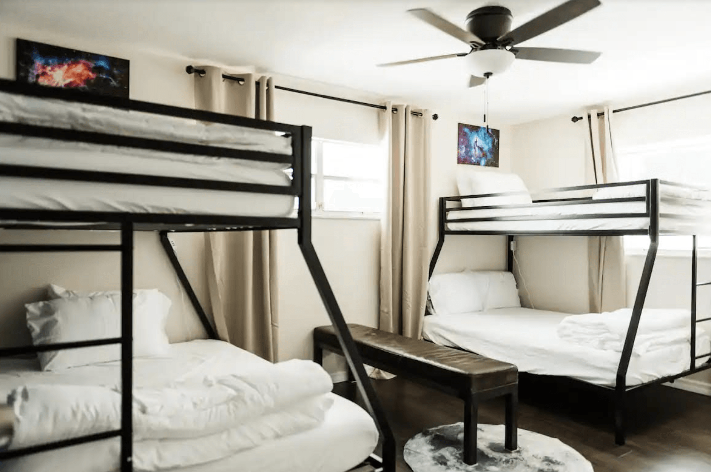 A room with four bunk beds and a ceiling fan.