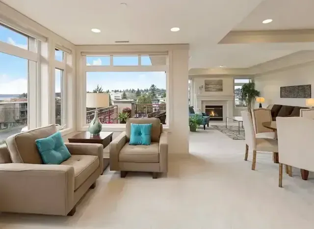 Bright living room with beige sofas, teal pillows, and large windows overlooking a scenic view