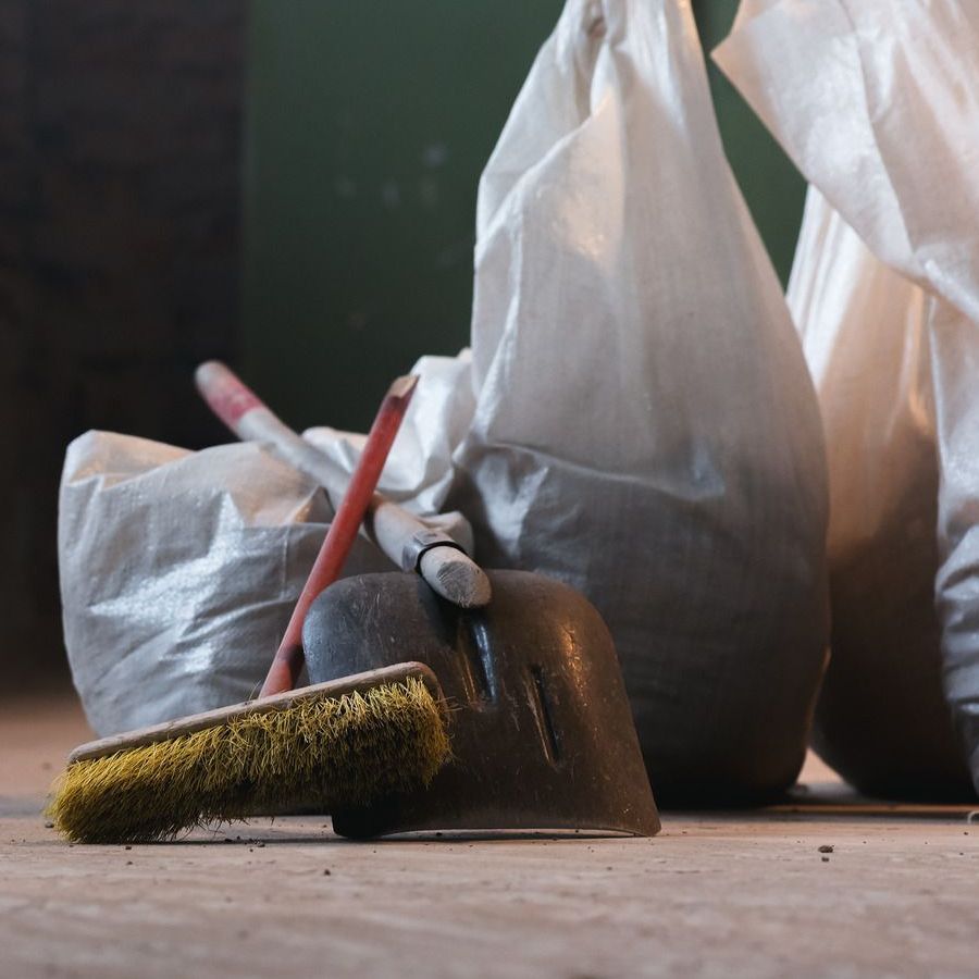 A blue broom is sitting on a wooden floor next to a ladder.