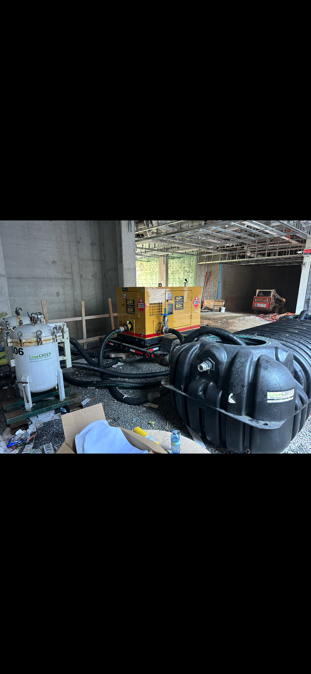A technician in uniform uses a portable filtration machine to clean heating system water in a mechanical room.