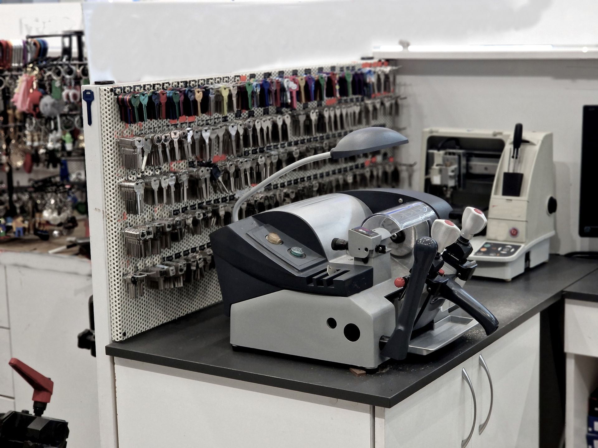 A key cutting machine is sitting on a counter in a key cutting shop.