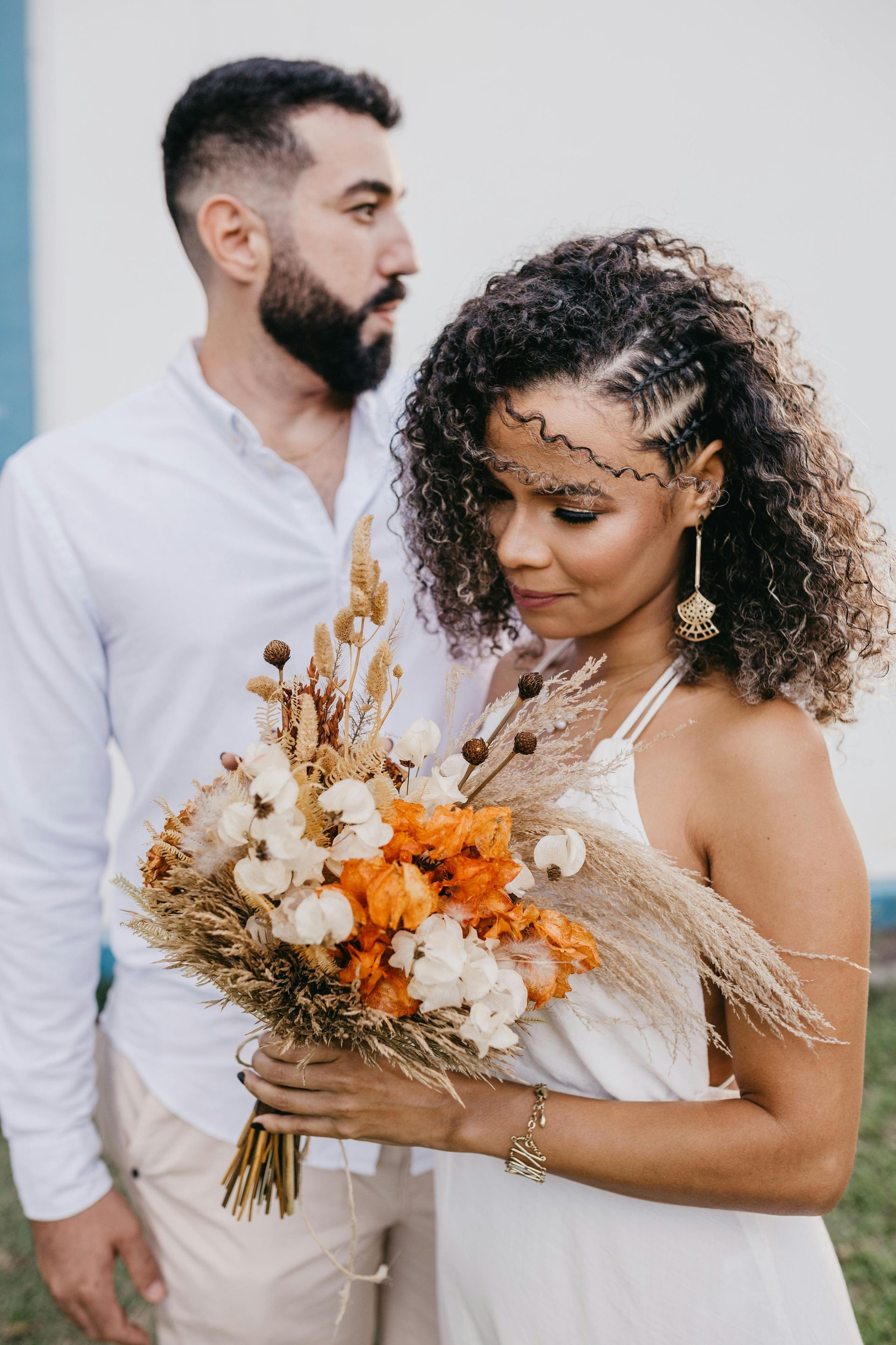 A man and a woman are standing next to each other and the woman is holding a bouquet of flowers.