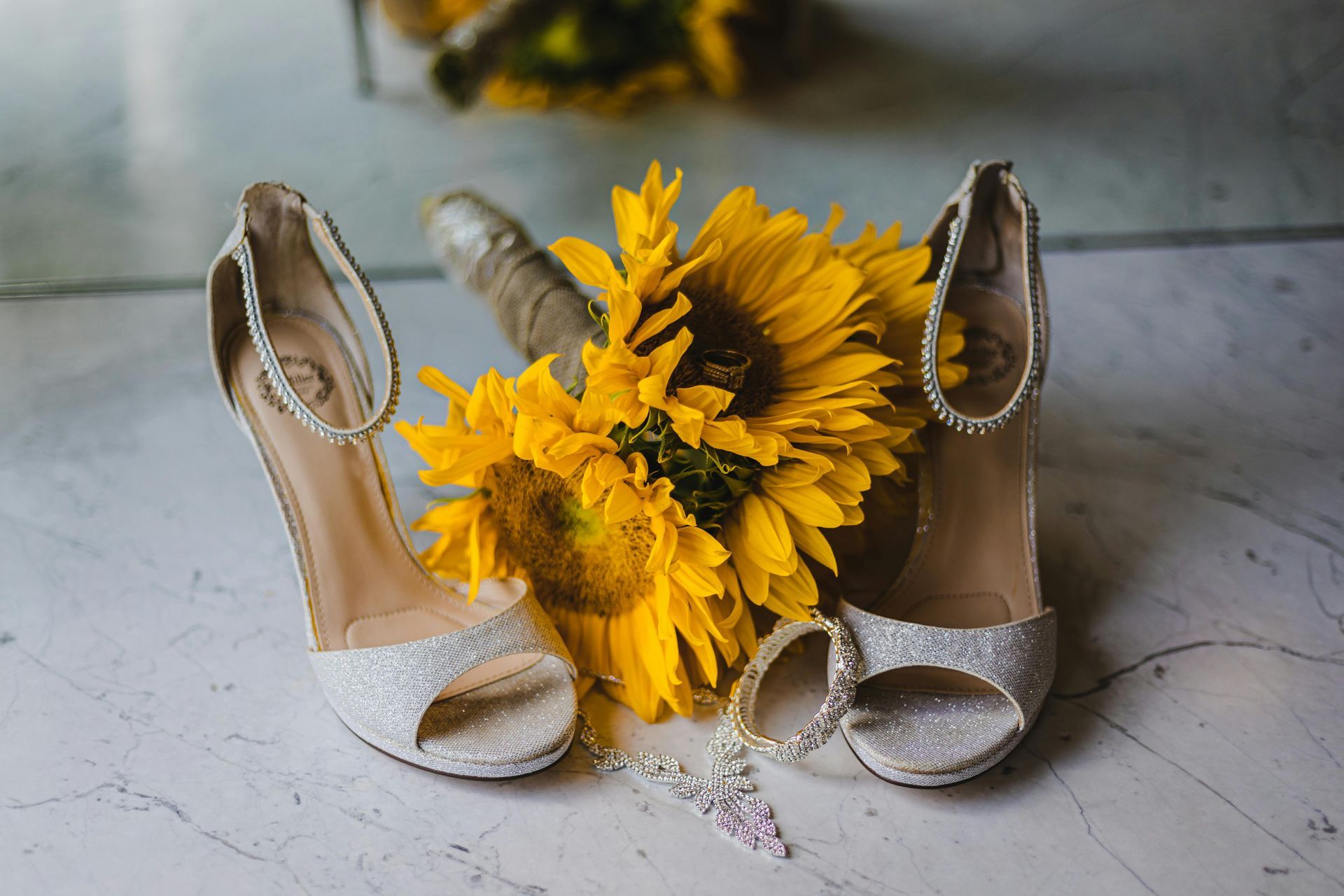 A pair of wedding shoes and a bouquet of sunflowers on a table.