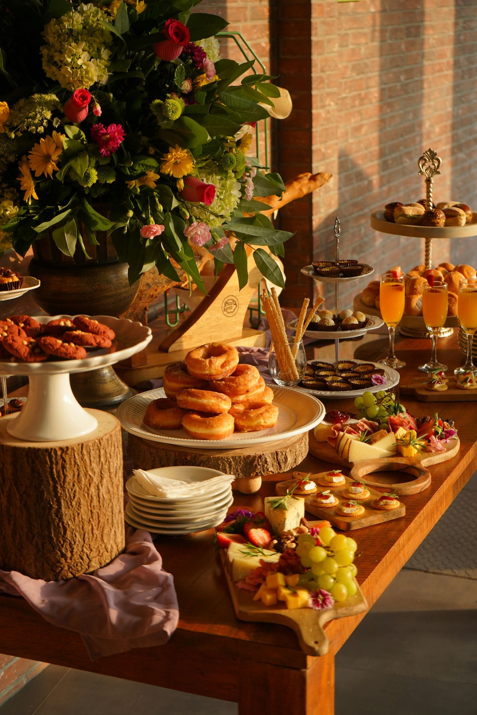 A wooden table topped with a variety of food and a vase of flowers.