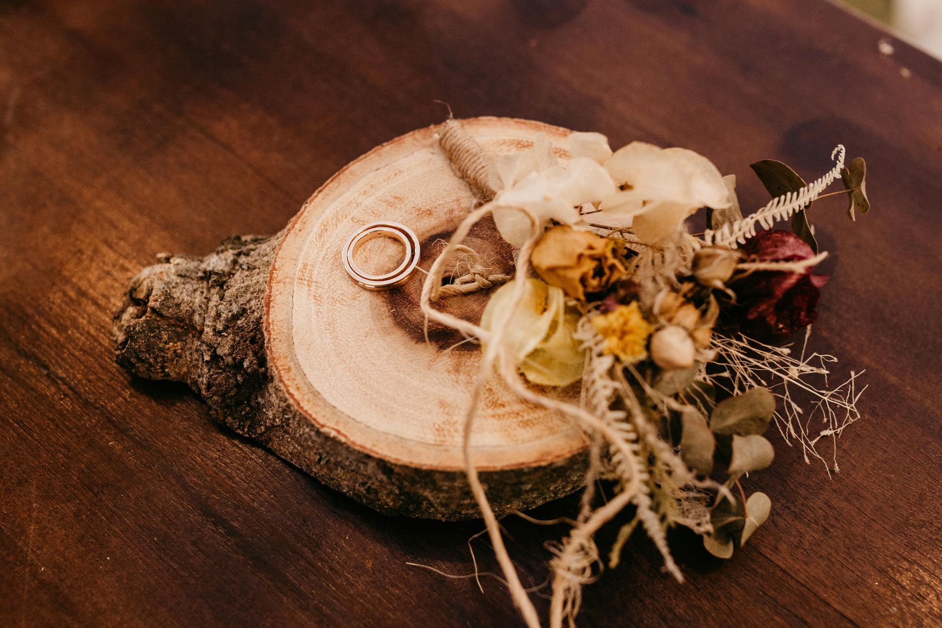 A couple of wedding rings sitting on top of a wooden slice.