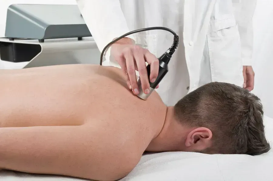 Person receiving shoulder treatment with a medical device.
