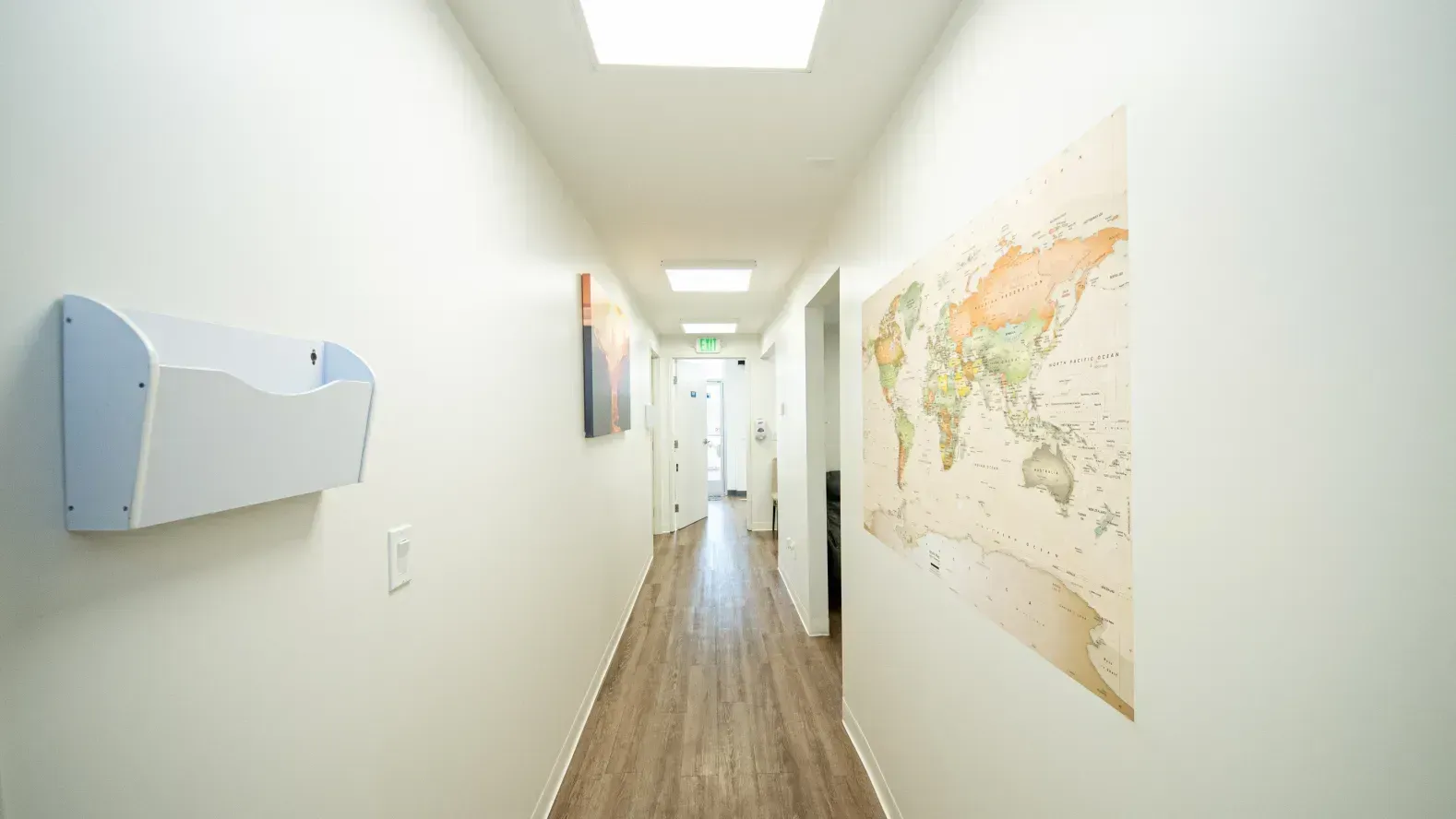 Hallway with world map, white walls, wooden floor, and white mailbox.