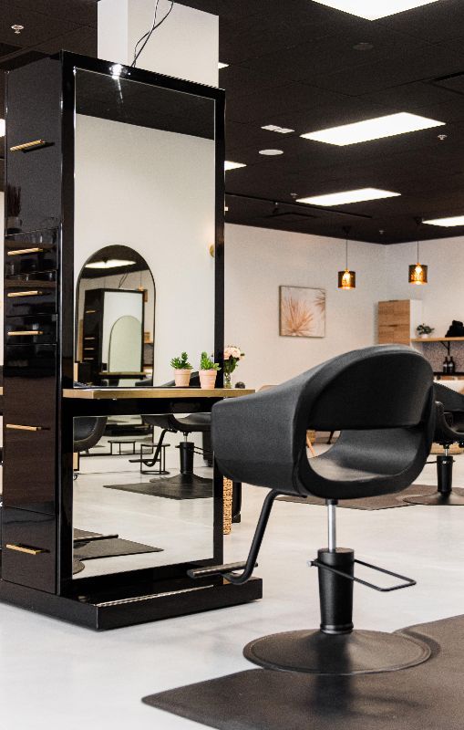 Modern salon interior with black styling chair, mirror station, and ceiling lights