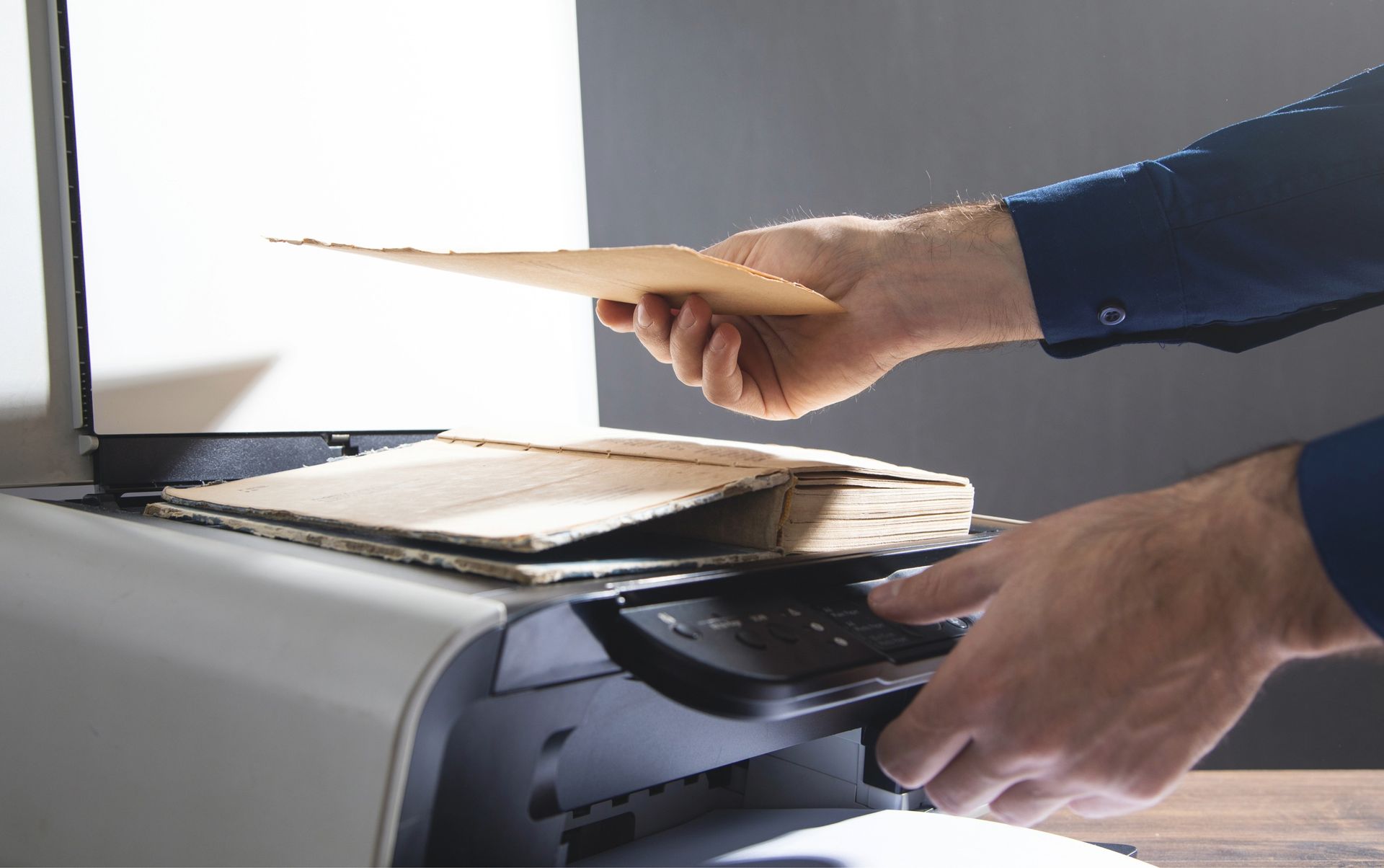 Person feeding a document into a machine, likely a printer or scanner, in an office setting.