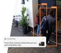 Two people at a front door with orange detection boxes from a security camera app overlay