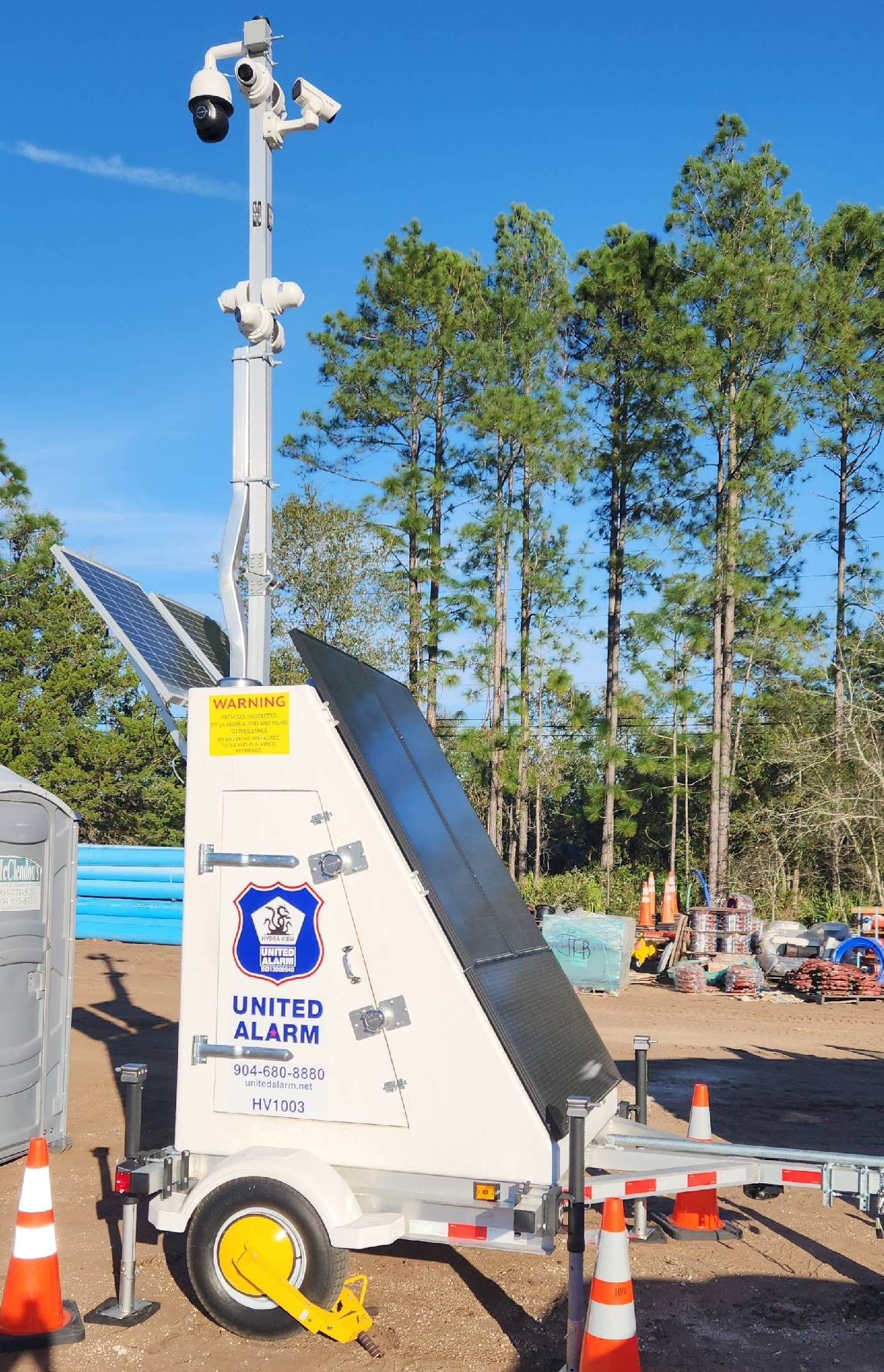 Portable solar-powered trailer with raised mast and cameras in a parking lot, cones around it