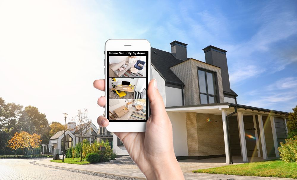 Hand holding a phone showing a home app in front of a modern house and suburban street