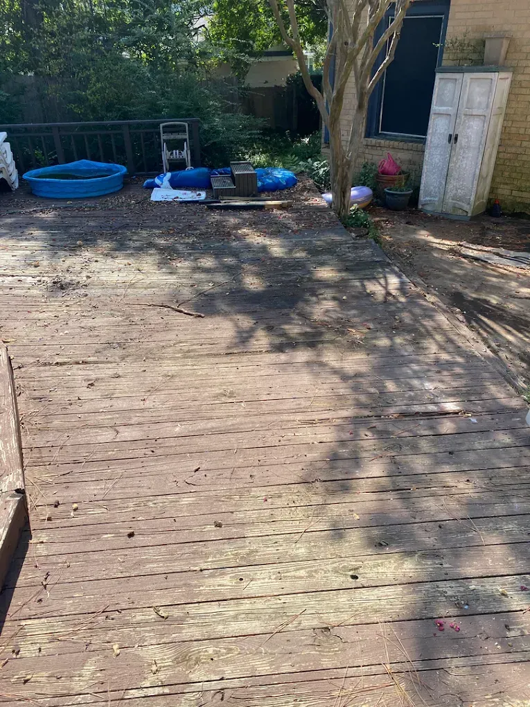 A weathered, brown wooden deck leads to a backyard with a blue plastic pool, a small white shed, and various yard items.