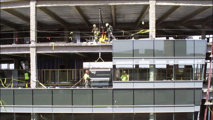 Construction workers on a steel-framed building exterior under a roof structure