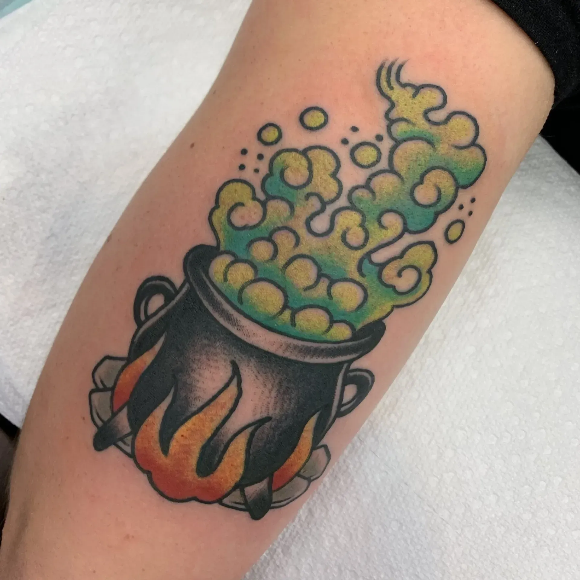 A tattoo of a cauldron with smoke coming out of it