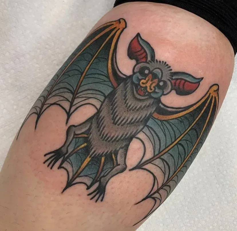 A person has a tattoo of a bat on their leg