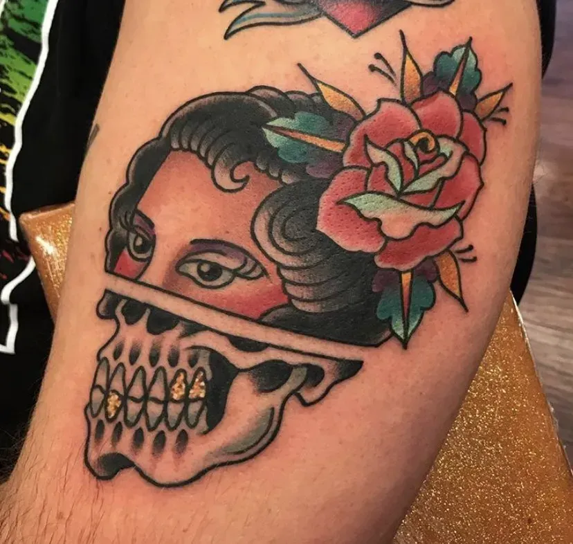A tattoo of a woman 's face on a skull with a rose in her hair
