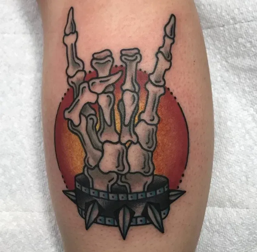 A tattoo of a skeleton hand making a horn sign