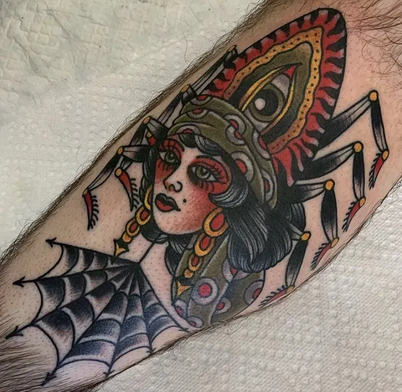 A tattoo of a woman with a spider on her arm.