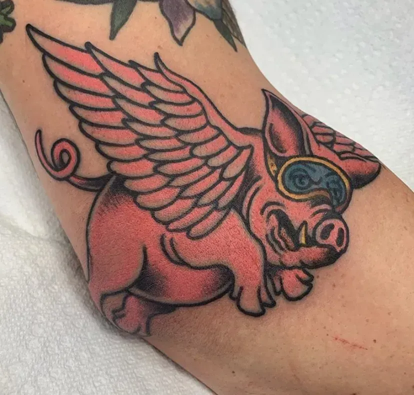 A tattoo of a pig with wings and goggles