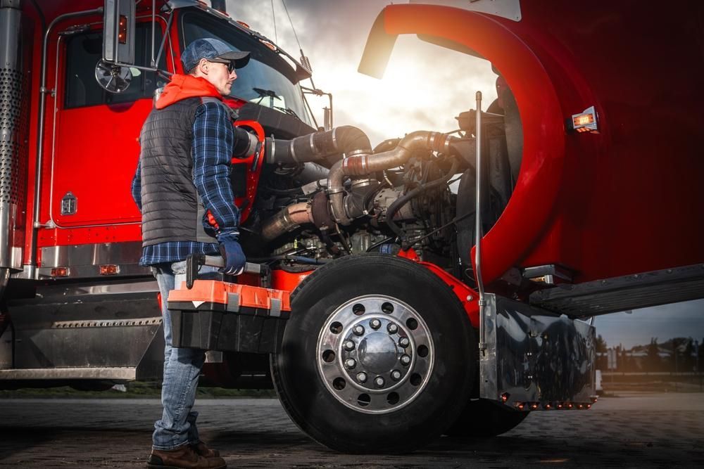 Trucker inspecting semi-truck engine with open hood, bright sunlight.