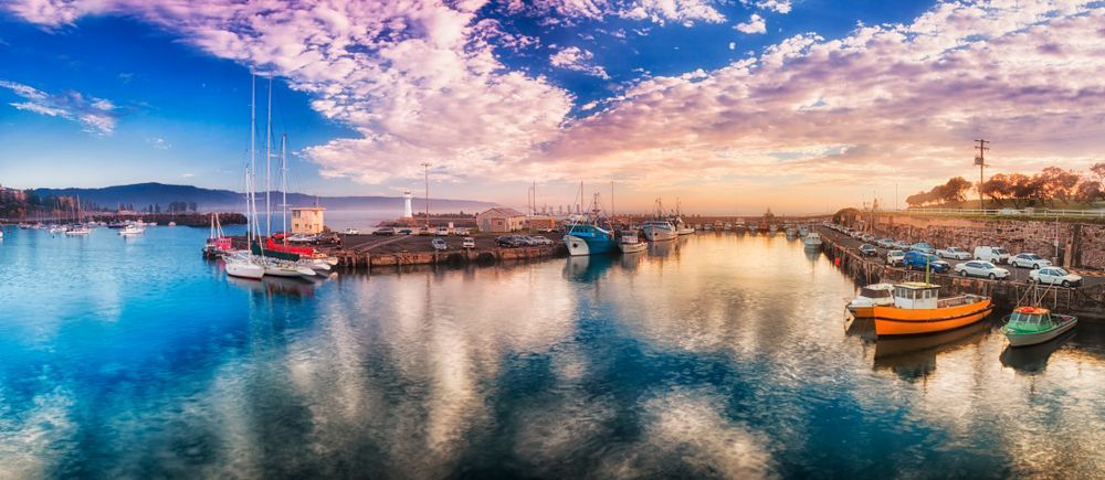 A Group of Boats Are Docked in a Harbor at Sunset — Complete Clean Home Cleaning in Northern Illawarra, NSW