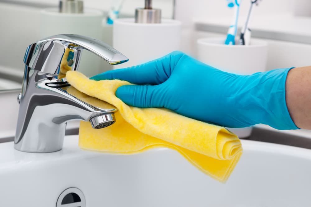 A Person Wearing Blue Gloves Is Cleaning a Bathroom Sink — Complete Clean Home Cleaning in Warrawong, NSW