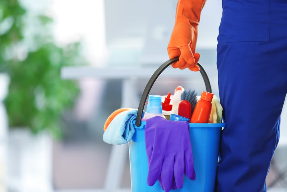 A Person Is Holding a Bucket of Cleaning Supplies — Complete Clean Home Cleaning in Primbee, NSW